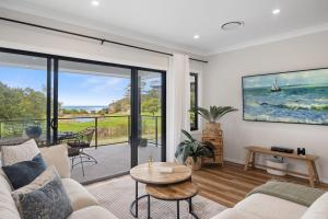 a living room with a couch and a table at Ahgunyah Beach House in Mollymook