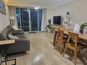 a living room with a black leather couch and a table at Oceanfront Ground Floor Apartment - Dwell 3 in Bargara in Bargara +33 photos