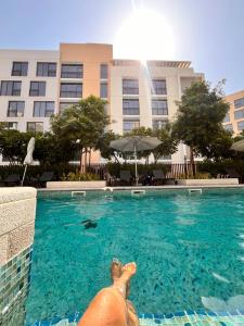 a person laying in a swimming pool in front of a building at The Opal residence IBR in Sharjah