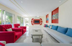 a living room with red and blue couches and a tv at Villa de Luxe à Marrakech avec Piscine Chauffée Privée in Aghmat