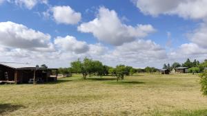a field with a barn and trees and clouds at Casas para 6 personas in Juan L. Lacaze