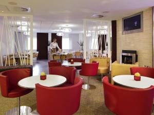 a restaurant with white tables and red chairs at ibis Aberdeen Centre – Quayside in Aberdeen