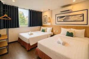 a hotel room with two beds and a window at Hoang Phi Saigon Hotel & Spa in Ho Chi Minh City