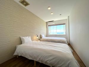 two beds in a small room with a window at 貸別荘 波音と朝日 namine to ASAHI in Miyazu