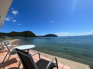 a deck with chairs and a table and the water at 貸別荘 波音と朝日 namine to ASAHI in Miyazu
