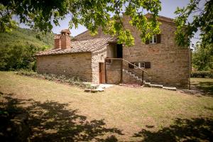 una vecchia casa in pietra con una scala in un cortile di Borgo Al Teto Il Gelso a Castiglion Fiorentino