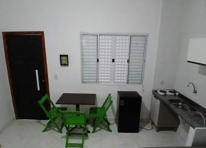 a kitchen with green chairs and a table and a window at Kitnet 2 confortável com piscina em Pontal do Sul in Pontal do Paraná +2 photos
