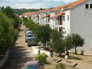 2 personnes marchant dans une rue à côté d'une rangée de maisons dans l'établissement Studio Apartment Jadranko, à Krnica
