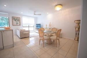 a kitchen and dining room with a table and chairs at Montipora Luxe Beachside Apartment in Airlie Beach