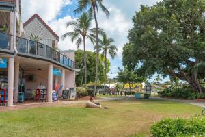 a woman sitting in a park next to a playground at Montipora Luxe Beachside Apartment in Airlie Beach