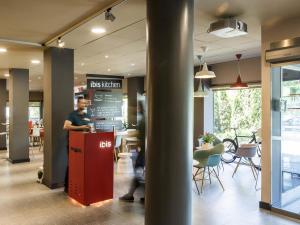 a man standing at a counter in a restaurant at Ibis Montmelo Granollers in Granollers