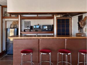 a kitchen with a bar with red stools at 海の見える高台に佇む隠れ家宿 #貸別荘 #一棟貸切 #グループや家族旅行におすすめ #テラスで海を眺めながらBBQ #屋内でもBBQ可 #BBQグリル付 #大洗 #鉾田 #umibe in Hokota