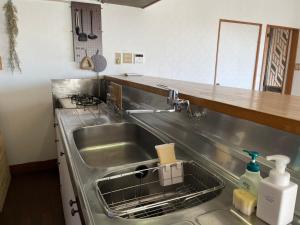 a kitchen with a stainless steel sink and a counter at 海の見える高台に佇む隠れ家宿 #貸別荘 #一棟貸切 #グループや家族旅行におすすめ #テラスで海を眺めながらBBQ #屋内でもBBQ可 #BBQグリル付 #大洗 #鉾田 #umibe in Hokota