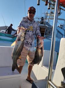 un homme debout sur un bateau détenant deux poissons dans l'établissement Hotel Melyvan, à San Carlos