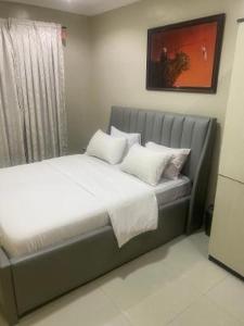 1 cama con almohadas blancas en un dormitorio en Peony Apartment, en Lagos