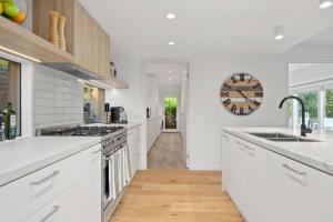 Casa del Sol Heated Pool & Spa في سورينتو: مطبخ مع دواليب بيضاء وساعة على الحائط