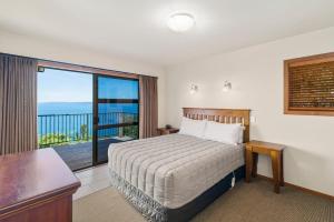 a hotel room with a bed and a balcony at Oreti Village Resort in Kuratau +5 photos