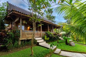 a house with a porch and stairs in a garden at Taksu Sebatu Villa in Ubud