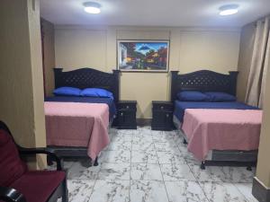 a bedroom with two beds with pink sheets and blue pillows at Xelaju Hotel in Quetzaltenango