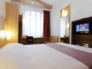 a hotel room with a bed and a flat screen tv at ibis Paris Tour Montparnasse 15eme in Paris