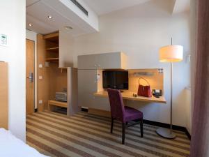 a hotel room with a desk with a chair and a television at Mercure Hotel Aachen Am Dom in Aachen