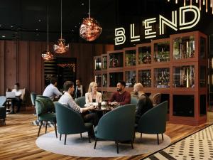 a group of people sitting around a table in a restaurant at PULLMAN Berlin Schweizerhof - City Center, Zoo und Kurfürstendamm in Berlin