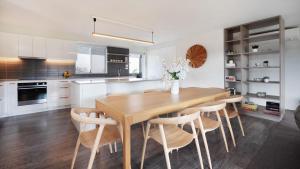 a kitchen with a wooden table and some chairs at Surf N Turf in Kiama