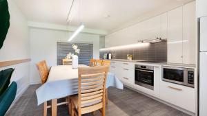 a kitchen with white cabinets and a table and chairs at Surf N Turf in Kiama