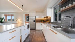 a kitchen with white cabinets and stainless steel appliances at Surf N Turf in Kiama