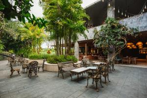 an outdoor patio with chairs and tables and trees at ONYX PARK RESORT Ubud in Ubud