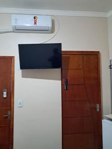 a room with a tv on the wall and a door at Suite Família a 10min do aeroporto in Guarulhos