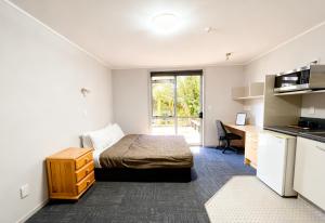 a bedroom with a bed and a desk and a kitchen at Heaphy Apartment in Hamilton