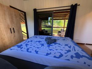 a bedroom with a bed with a blue comforter at Moana Lodge in Raiatea