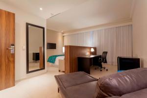 a hotel room with a desk and a bed at Tulip Inn Sete Lagoas in Sete Lagoas
