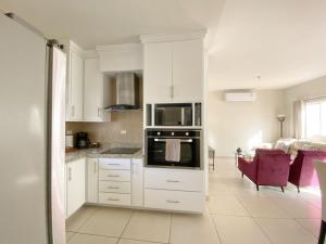 a kitchen with white cabinets and a stove top oven at Casa Atardecer con Alberca en Privada, 5 min del Aeropuerto y Consulado Americano in Hermosillo