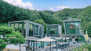 a building with tables and umbrellas next to a mountain at Avec J Pool Villa in Samgŏ-ri