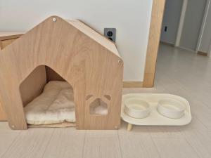 a wooden dog house with two bowls in it at Gapyeong Relaxing Pension in Yŏnbyŏn