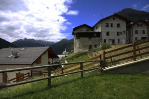 ein Gebäude auf einem Hügel mit einem Zaun und Häusern in der Unterkunft Baita Muffe' in Valdidentro