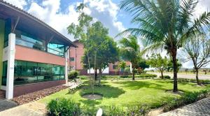 a building with a park with palm trees in front of it at Flat espaçoso e confortavel no hotel Canarius Gravata in Gravatá