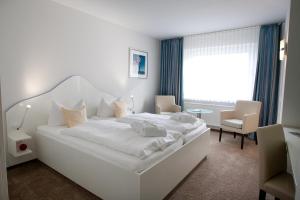 una camera bianca con un grande letto bianco e un tavolo di Frühstückshotel Seemannsbraut Amrum-adults only ab 18 Jahre-keine Haustiere- a Wittdün
