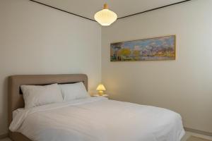 a bedroom with a white bed and a painting at Asan Wolang Stay in Asan +12 photos