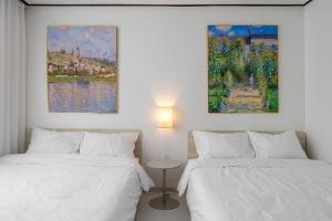 two beds with white sheets and a lamp in a room at Asan Wolang Stay in Asan