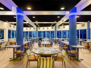 a dining room with tables and chairs and blue columns at Novotel Port Harcourt in Port Harcourt