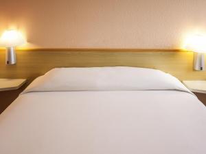 a large white bed with two lamps on both sides at ibis Betim in Betim
