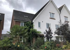a white house with a black roof at Lovely Room with a view & Parking nr Hampton Court in West Molesey