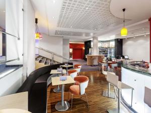 a restaurant with a bar with stools and tables at Ibis Praha Old Town in Prague