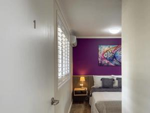 - une chambre avec un lit et un mur violet dans l'établissement Quarterdeck Apartment 7 - Family Stay, à Gladstone