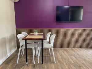 a table with white chairs and a purple wall at Quarterdeck Apartments in Gladstone +21 photos