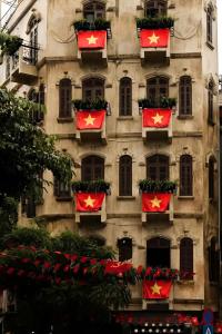 Una fachada de un edificio con banderas rojas y flores. en DEMO Inn & Ine - Poetic Studio Stay, en Hanói