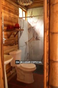 a bathroom with a toilet and a glass door at Cabañas Viva Mexico in Ibagué